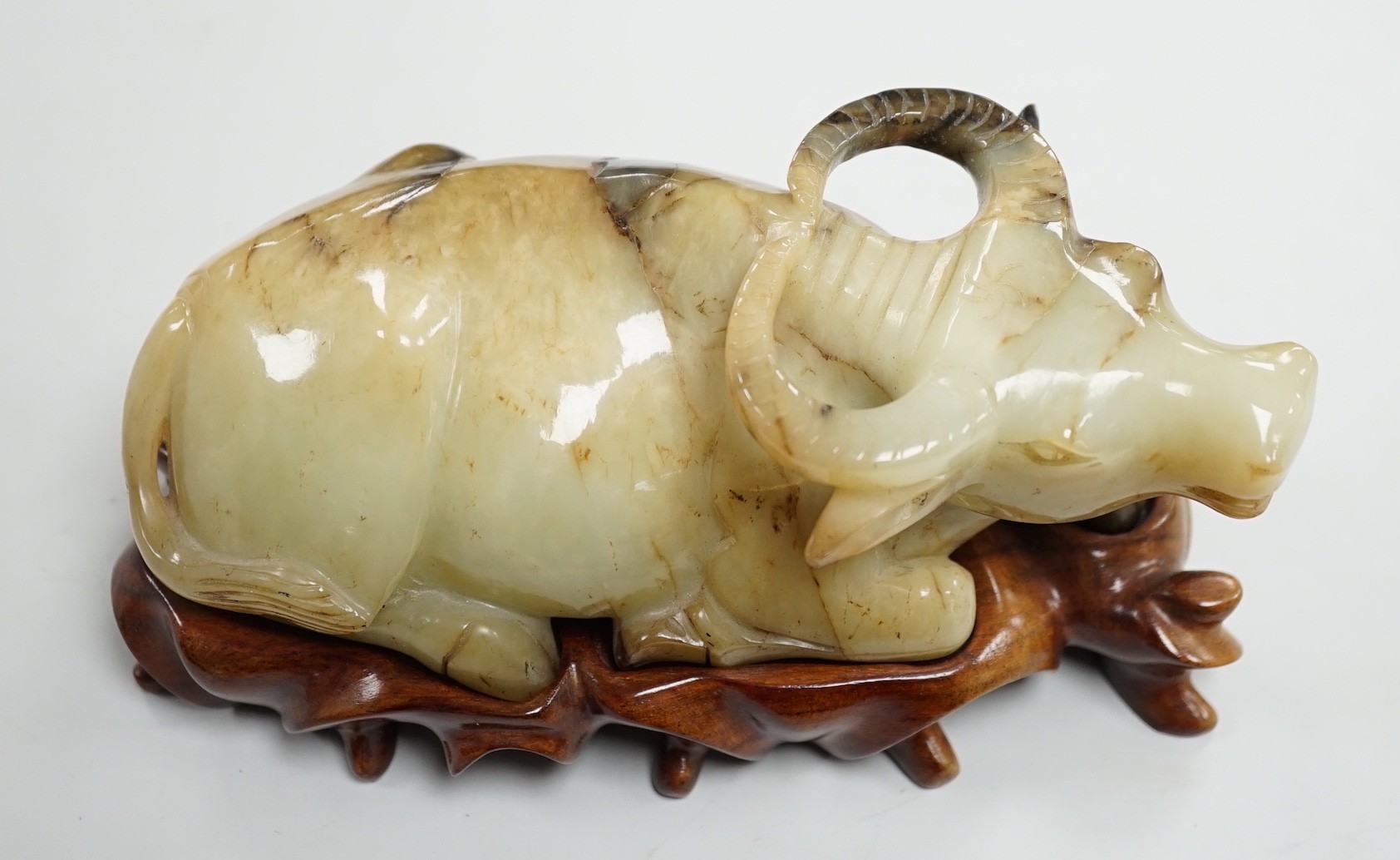 A large Chinese grey and black jade figure of a recumbent buffalo, 17cm long, wood stand